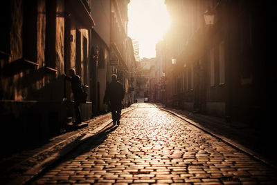 Men on cobbled street amidst buildings in city