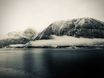 Scenic view of lake by snowcapped mountain against sky