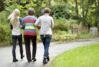 Rear view of three generation females walking on street at park