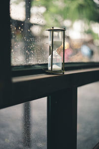 Close-up of hourglass by wet window in rainy season