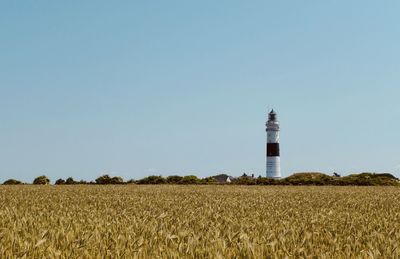 Lighthouse on field against clear sky