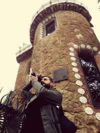 Low angle portrait of man against building against clear sky