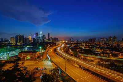Distant view of petronas towers against sky in illuminated city at dusk