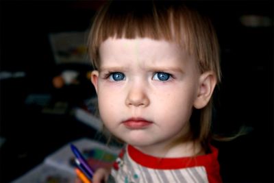 Close-up portrait of girl holding crayons at home