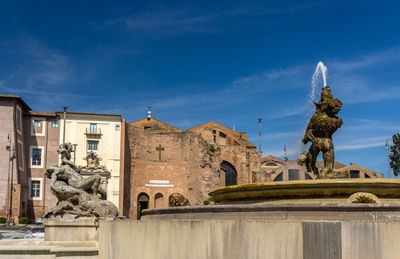 Statue amidst buildings against sky