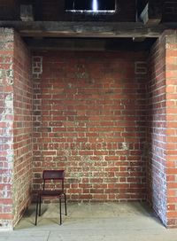 Empty chair against brick wall