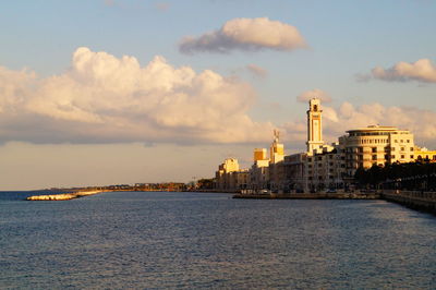 City at waterfront against cloudy sky