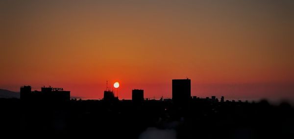 Silhouette buildings against sky during sunset