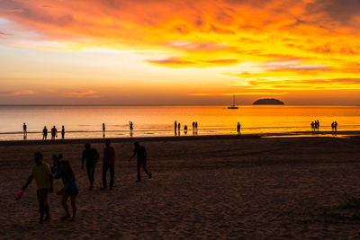 Silhouette people on beach against sky during sunset