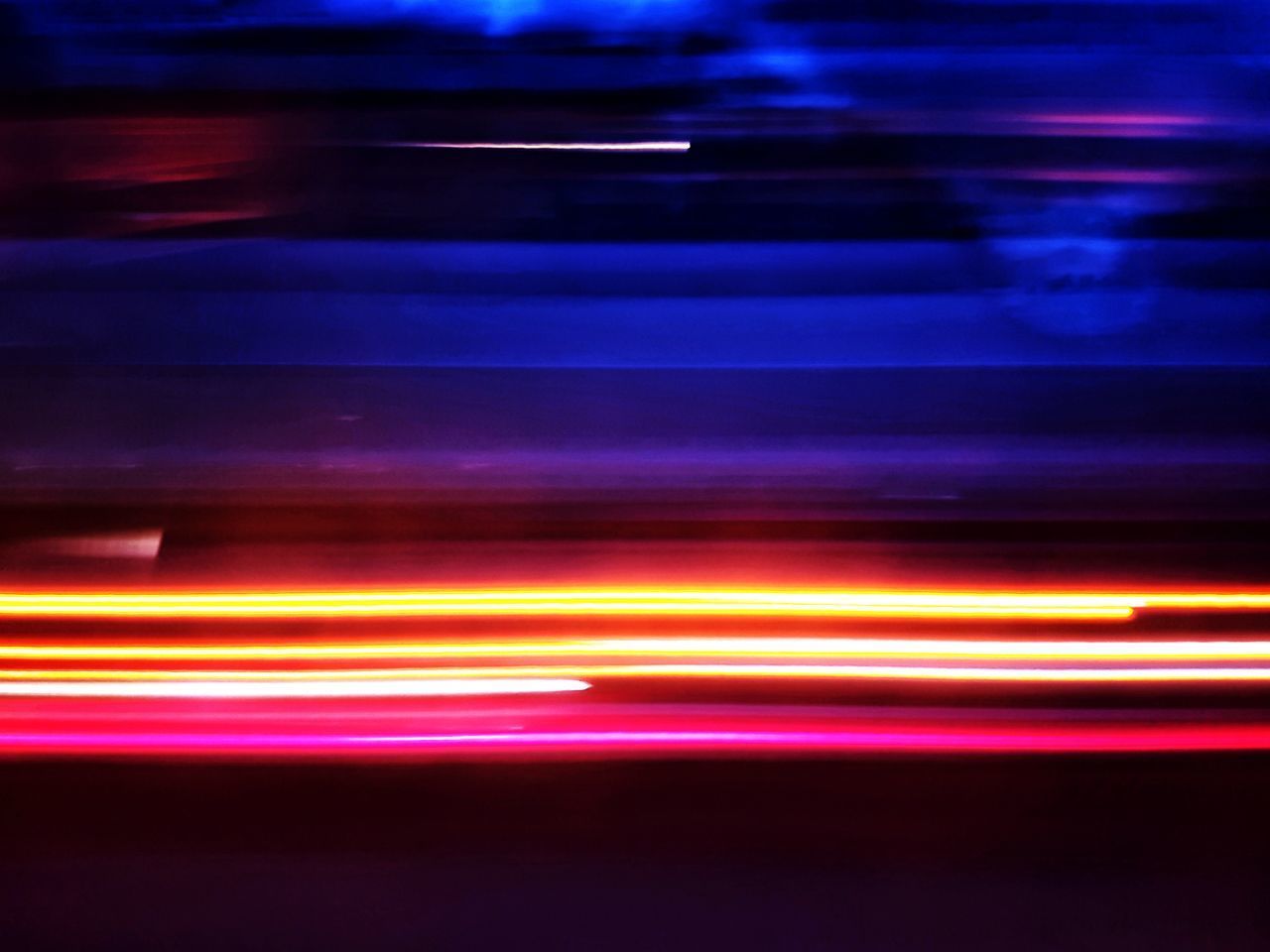 LIGHT TRAILS ON ILLUMINATED STREET AT NIGHT