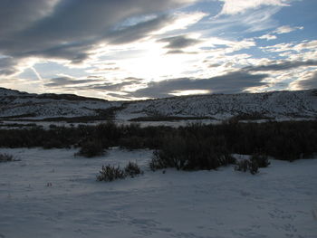 Scenic view of snow covered mountains against cloudy sky