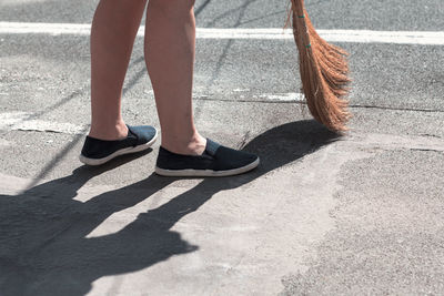 View of feet and broom . woman sweeping the street