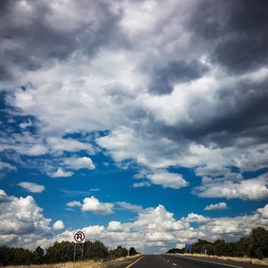Road sign against cloudy sky