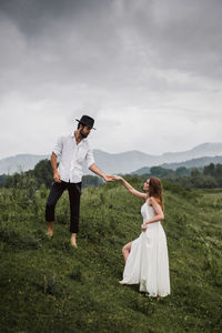 Young man holding hand of woman on field