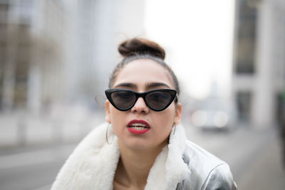 Portrait of woman in sunglasses against buildings