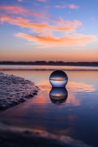 Reflection of stones on lake against sky during sunset