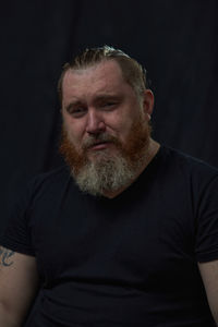 Portrait of serious man looking away against black background