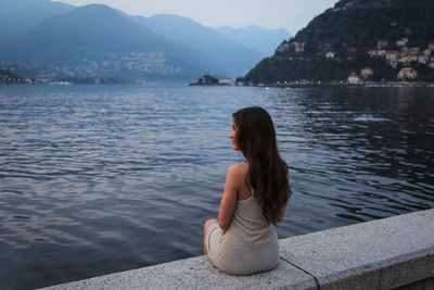 Rear view of woman sitting by lake