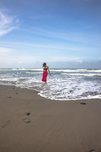 Woman standing on beach against sky