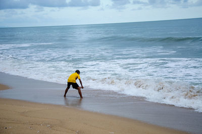 Rear view of person on sea shore against sky