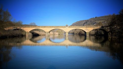 Arch bridge over lake against blue sky