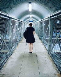 Rear view of woman standing in illuminated bridge