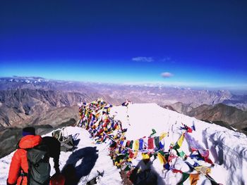 People by prayer flags on snowcapped mountain against sky