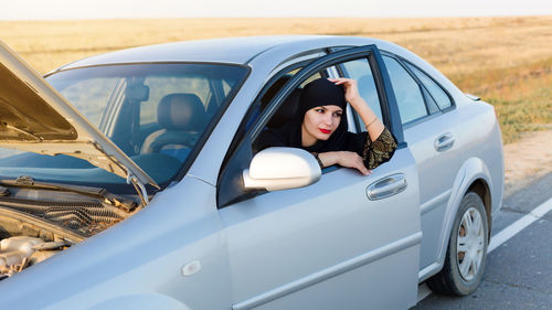 Smiling woman looking away while sitting in car