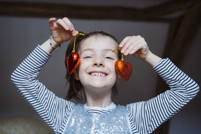 Portrait of smiling girl holding heart shaped decorations