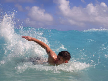 Young man swimming in infinity pool against sky