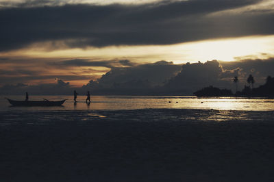Silhouette people on beach against sky during sunset