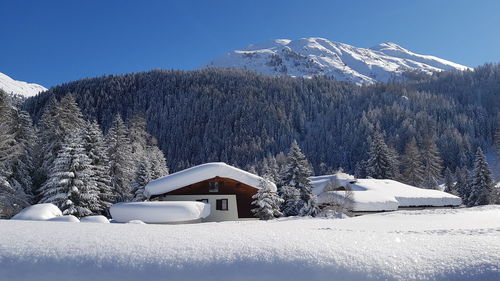 House on snowcapped mountain against sky