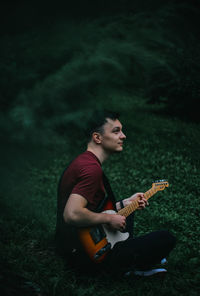 Young man playing guitar on field