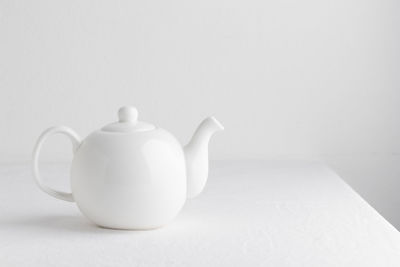 Close-up of teapot on table against white background