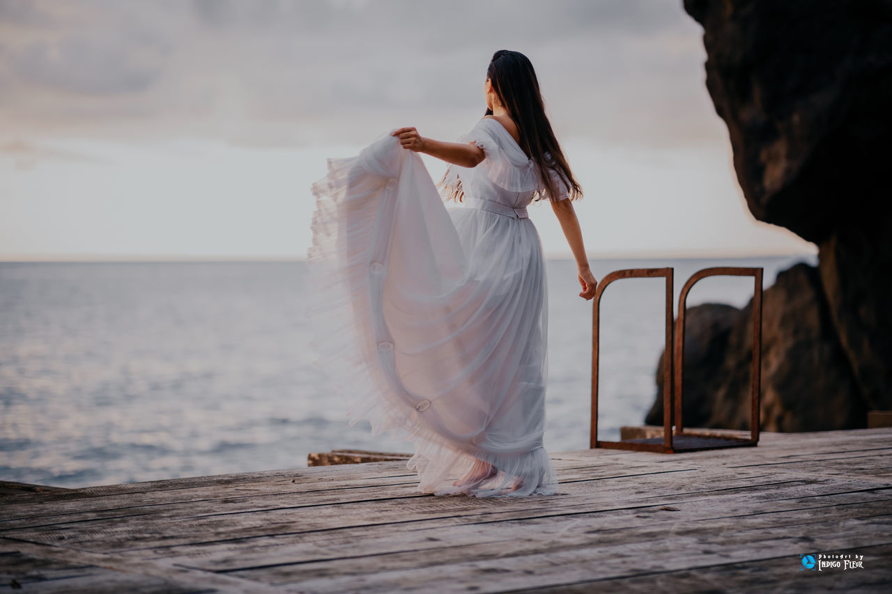 WOMAN STANDING ON BEACH AGAINST SEA