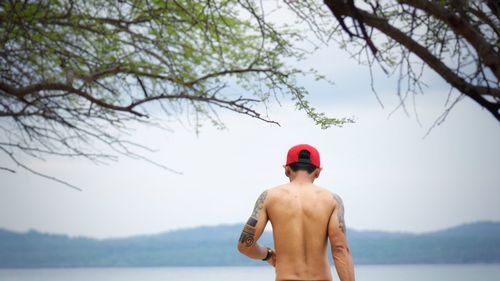 Rear view of shirtless man standing against sky