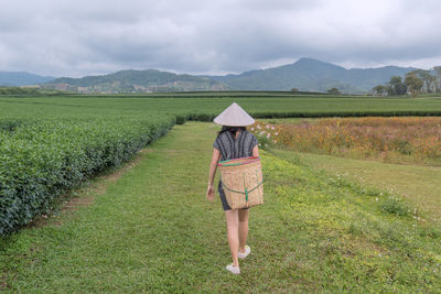 Full length of woman walking on field against sky