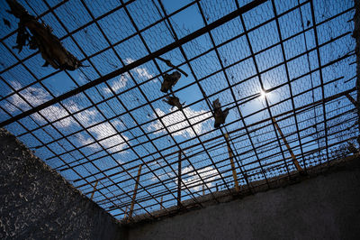 Low angle view of metal fence against blue sky