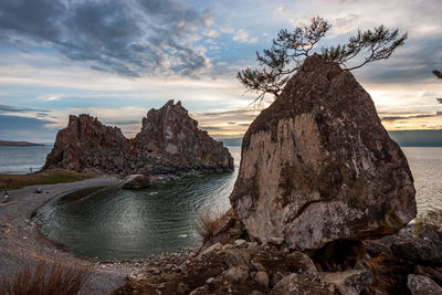 Rock formation on beach against sky during sunset