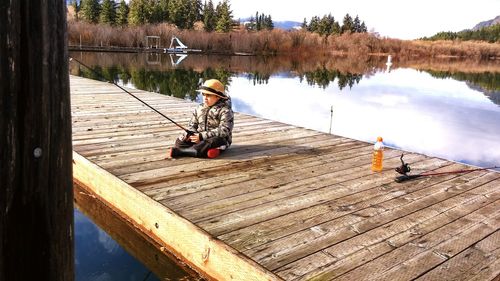 Man fishing on lake against sky