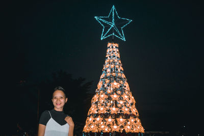 Portrait of young woman standing against sky at night