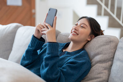 Young woman using phone on sofa