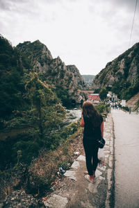 Rear view of woman walking on road against sky