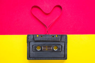 Close-up of gray audio cassette with heart shape against two tone background