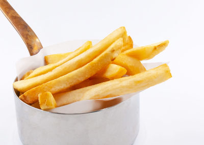 Close-up of fresh yellow fries against white background