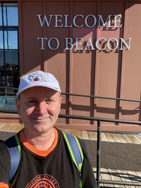 Portrait of smiling man standing against sign