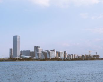 Sea and modern buildings in city against sky