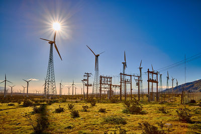 Wind turbines on field against bright sun