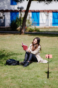 Young woman using mobile phone while sitting on grass