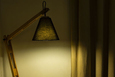 Low angle view of illuminated lamp hanging on wall at home